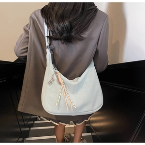 Light blue hobo tote bag in matte PU leather with woven charm, worn on model shoulder