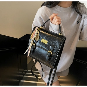 Détail du sac à dos noir gaufré avec foulard en soie et pendentif raquette dorée