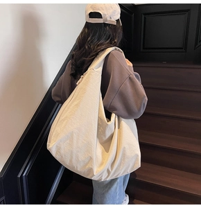 Detail view of a large cream hobo bag with pleated texture on a stylish shoulder strap