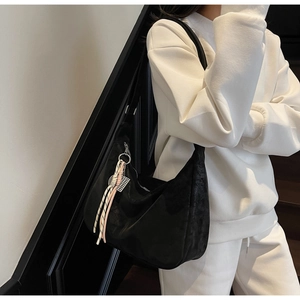 Detail of black crescent tote bag with pink tassel charm on casual white hoodie