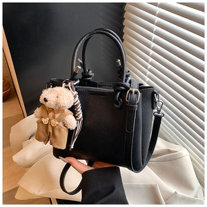 Detail van de zwarte bucket bag met een beer hanger en zilveren metalen gespen