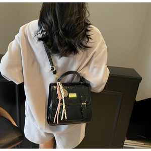 Détail d'un sac à main noir en cuir PU gaufré avec boucle dorée et décor de lanière