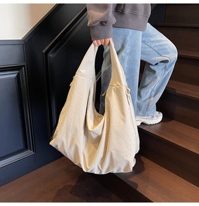 Detail of a large beige hobo shoulder bag showing its minimalist design and soft draping fabric