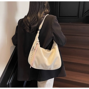 Minimalist creamy white tote bag with woven pink charm shown on a female model