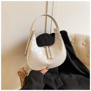 Detailed close-up of cream crocodile pattern crescent bag with dual zippers and smooth texture