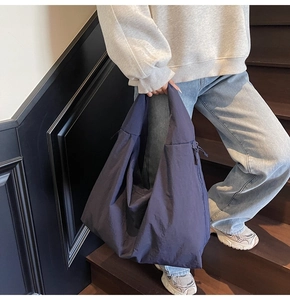 Detail of minimalist slouchy tote bag with smooth navy nylon fabric and side zipper pocket