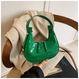 Close-up of vibrant green crocodile-embossed leather texture on a crescent hobo handbag