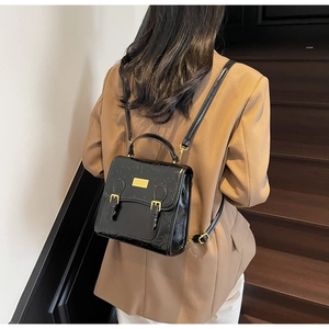 Détail du cuir gaufré noir et des boucles dorées sur un sac à dos au style vintage