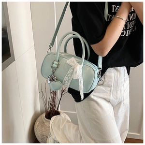 Détail du sac bowling bleu clair brillant avec nœud en dentelle et breloque cœur