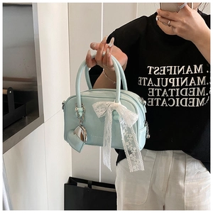 Vue détaillée d'un sac bowling vert menthe avec nœud en dentelle et pendentif cœur