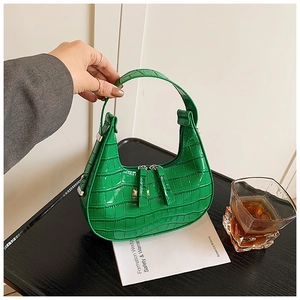 Detail of emerald green crocodile embossed texture on a crescent moon leather handbag