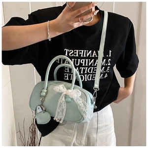 Détail du sac bowling bleu menthe avec un nœud en dentelle blanche et charme cœur