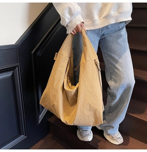 Detail of khaki nylon tote bag showing soft texture and metal zipper on model