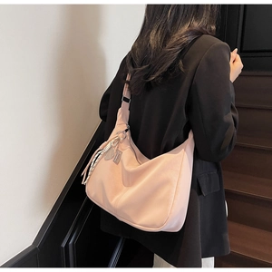 Detail of soft cream-style tote bag with vertical stitching and decorative pendant charm