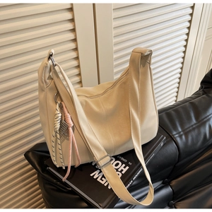 Close-up of cream white tote bag with adjustable strap and decorative rope charm detail