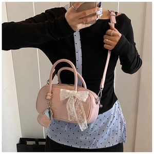 Détail du sac bowling rose avec nœud en dentelle blanche et breloque cœur