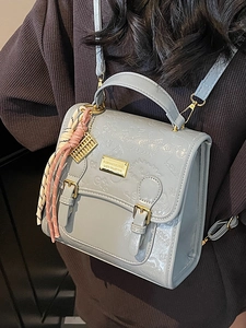 Sac à dos bleu clair avec motifs en relief, finitions dorées et pendentif pompon
