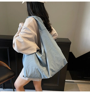 Detail view of light blue nylon tote bag showing its soft texture and wide shoulder strap