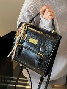 Sac bandoulière en cuir noir avec motifs monstres gaufrés et breloque raquette dorée