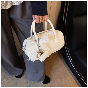 Détail du sac bowling blanc orné d'un nœud en dentelle et de pendentifs en cœur