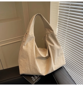 Detail view of beige tote bag with crinkled nylon fabric texture and wide shoulder strap