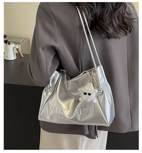 Macro shot of silver metallic tote bag with embossed logo and cute sheep plush charm