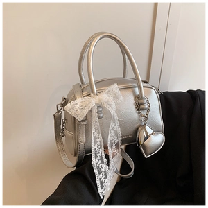 Vue détaillée du sac polochon argenté métallisé avec nœud en dentelle et cœur
