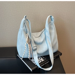 Detail of light blue hobo tote bag featuring lychee grain texture and woven cord charm