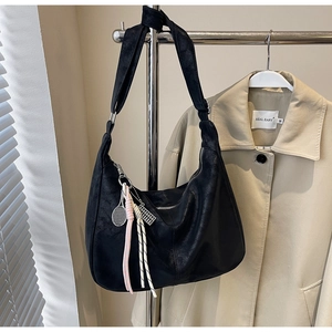 Detail of black matte crescent tote bag with tennis racket charm and wide shoulder strap