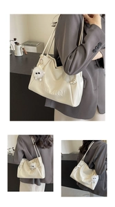 Detail of cream white tote bag with MIKAXIQI embossing and plush charm pendant