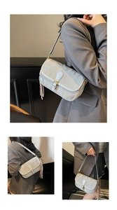Detail der grauen Schultertasche mit Marmortextur und gewebtem Quastenanhänger