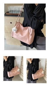 Detailed view of pink leather tote bag with embossed letters and plush charm accessory