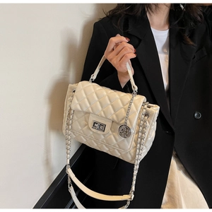 Close-up of beige quilted crossbody bag with chain strap and silver twist-lock closure