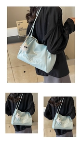 Detail of light blue faux leather tote bag featuring embossed logo and plush charm
