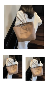 Detail view of khaki leather tote bag featuring a practical metal zipper front pocket