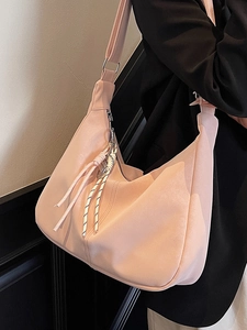 Pink hobo crossbody bag with large capacity and adjustable strap worn on black suit