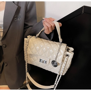 Detail of cream quilted bag showing leather chain strap and silver twist lock