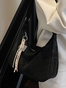 Minimalist black hobo tote bag with braided rope charm shown on shoulder for daily commute