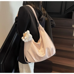 Détail du grand sac cabas en cuir souple abricot avec un pendentif d'ours blanc