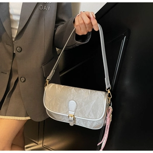 Detailansicht der silbernen Plissee-Baguette-Tasche mit rosa Knoten-Anhänger und Schnalle
