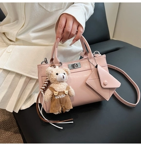 Vue détaillée d'un sac à main rose clair avec fermoir argenté et breloque ours en peluche