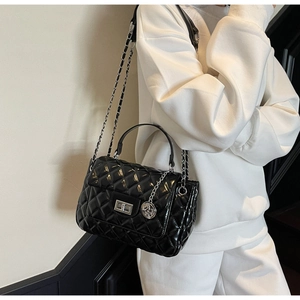 Detail of black quilted crossbody bag with metal twist lock and chain strap
