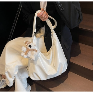 Grand sac hobo en similicuir blanc porté par un mannequin avec un charmant ours en peluche