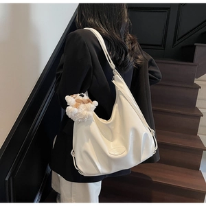 Vue détaillée d'un grand sac cabas blanc en cuir souple avec un pendentif ours en peluche