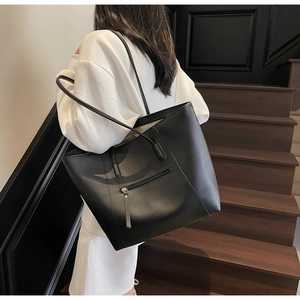 Detail view of large black tote bag with side zipper on model against dark stairs