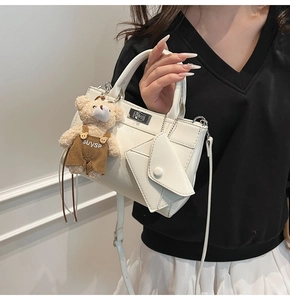 Détail d'un sac blanc brillant avec une breloque d'ours et un mini porte-monnaie