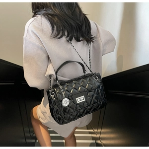 Quilted black chain crossbody bag with silver turn-lock and metallic charm on a model