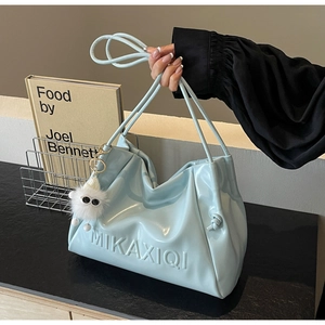 Detail of mint blue soft leather tote with pleats and cute white plush monster charm