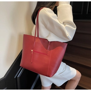 Detail of red synthetic leather tote bag with functional front zipper and slim straps