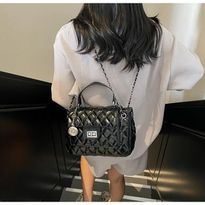 Detailed view of the quilted black leather handbag with silver chain strap on a model